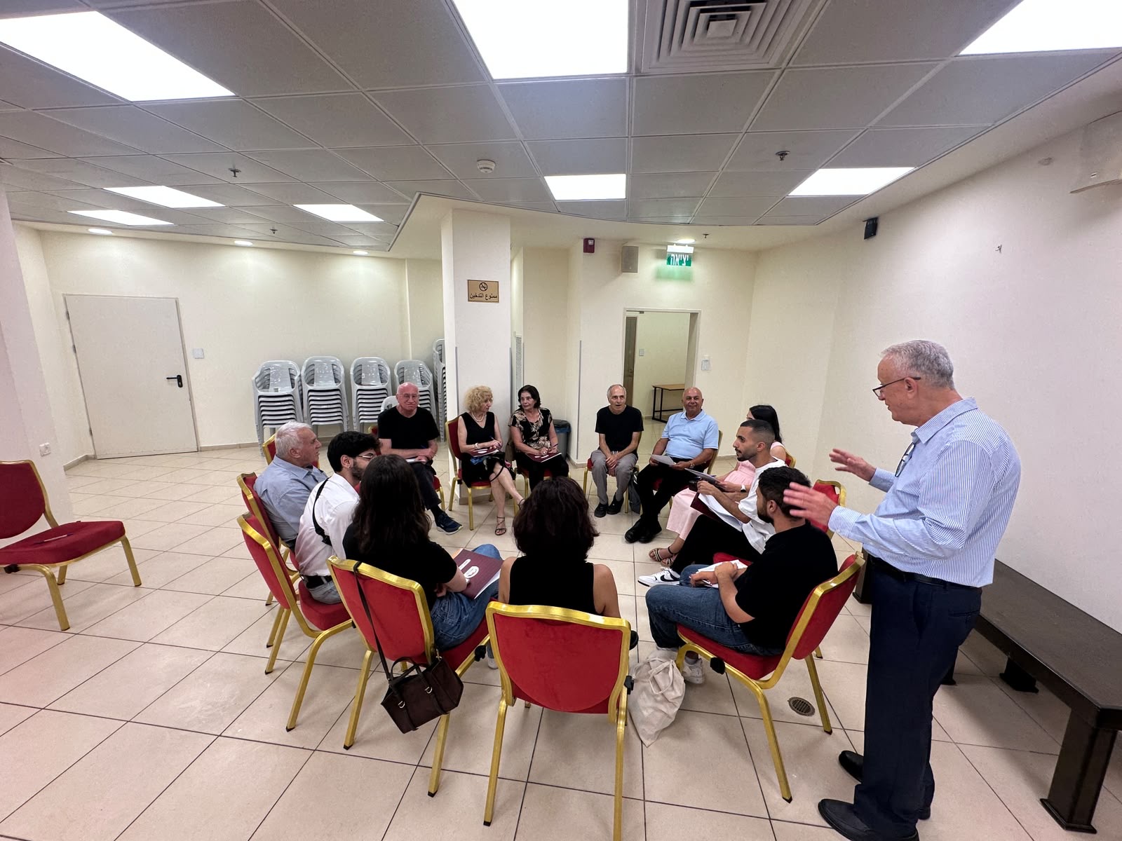 Participants of the founding assembly seated in a circle for a working-group discussion, mixed generations, one participant standing and speaking.